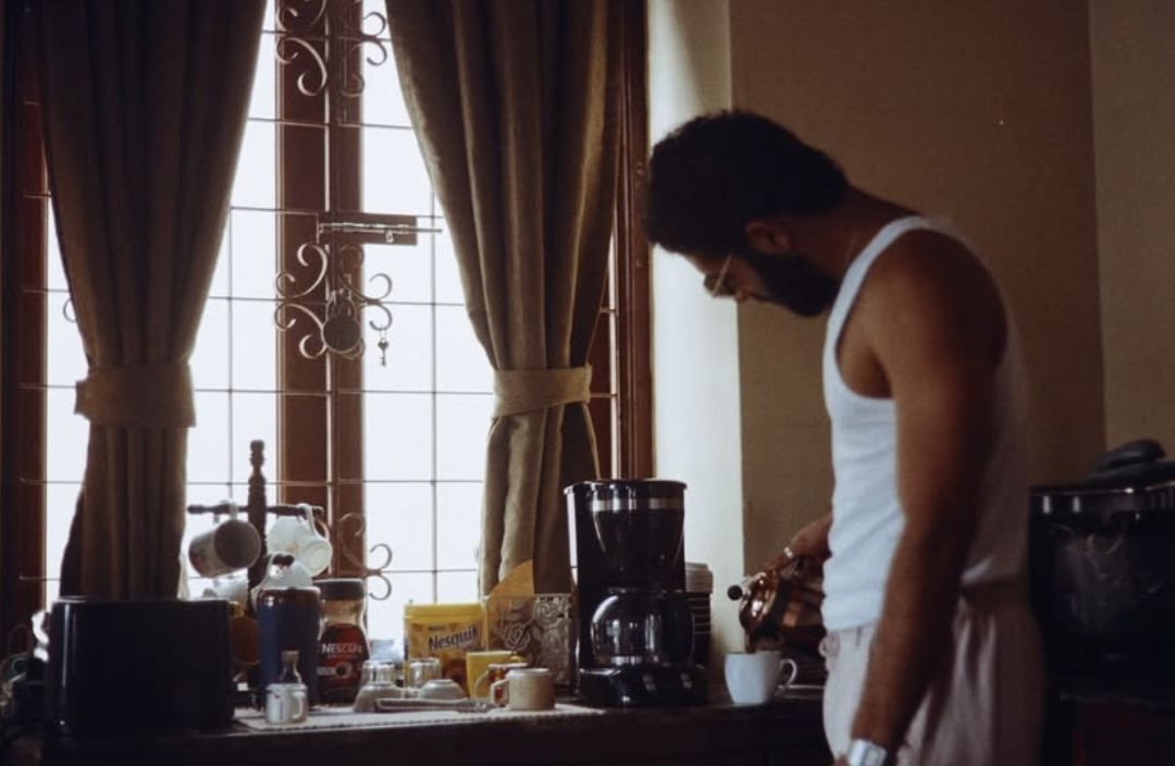 Azamaan pouring coffee by the window